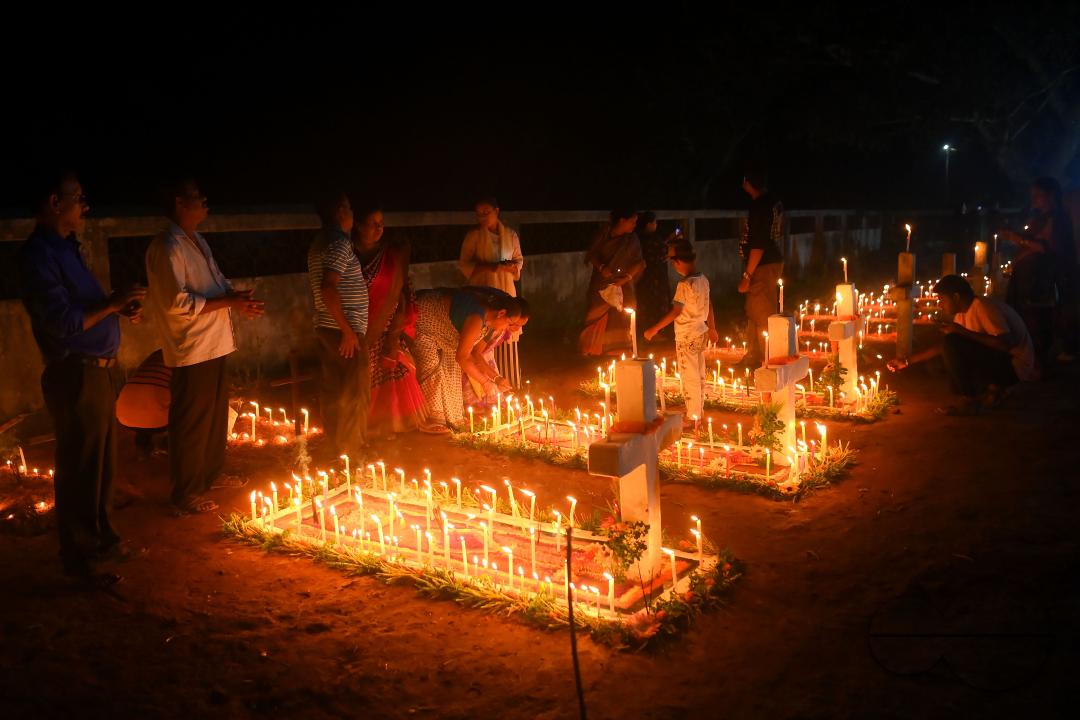 Christians offer prayers next to the graves of their family members at a cemetery during "All Souls Day" on the outskirts of Agartala