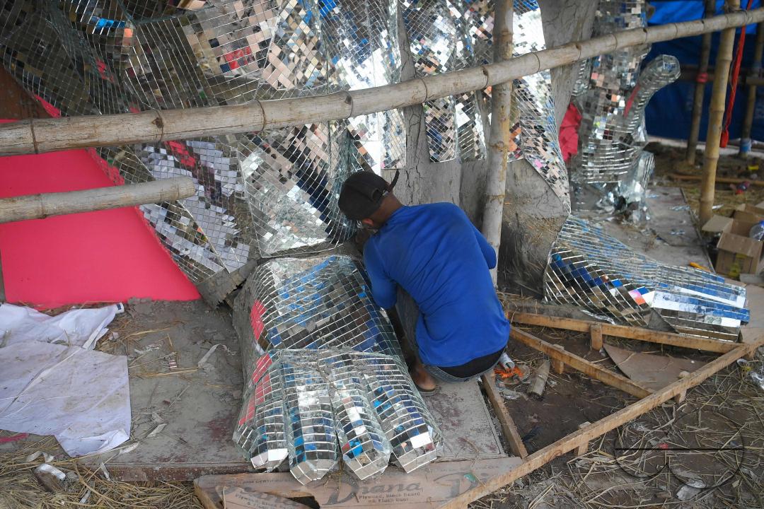 An artist is pasting glass pieces to make a 41 feet tall Ganesh idol, fully covered by glass, ahead of Ganesh Chaturthi festival in a pandal in Ranir bazar
