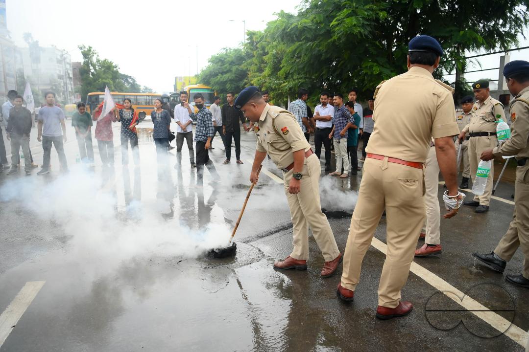A police officer is trying to control burning tyres during a protest by the supporters of the TSF (Twipra Students Federation) are protesting and demanding the introduction of Kokborok in Roman Script and passage of the 125th Constitutional Amendment Bil