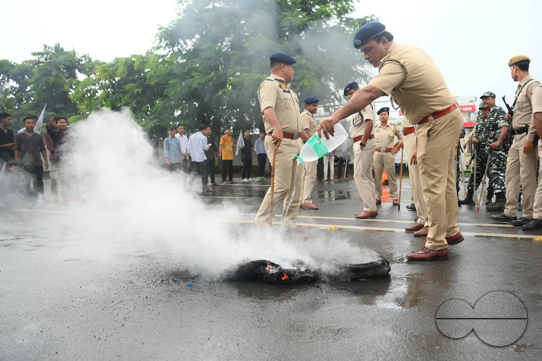 A police officer is trying to control burning tyres during a protest by the supporters of the TSF (Twipra Students Federation) are protesting and demanding the introduction of Kokborok in Roman Script and passage of the 125th Constitutional Amendment Bil