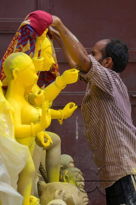An idol maker is covering an idol of the Mother Goddess Durga during a rainstorm in a studio, ahead of the Durga Puja festival in Agartala, Tripura, India.