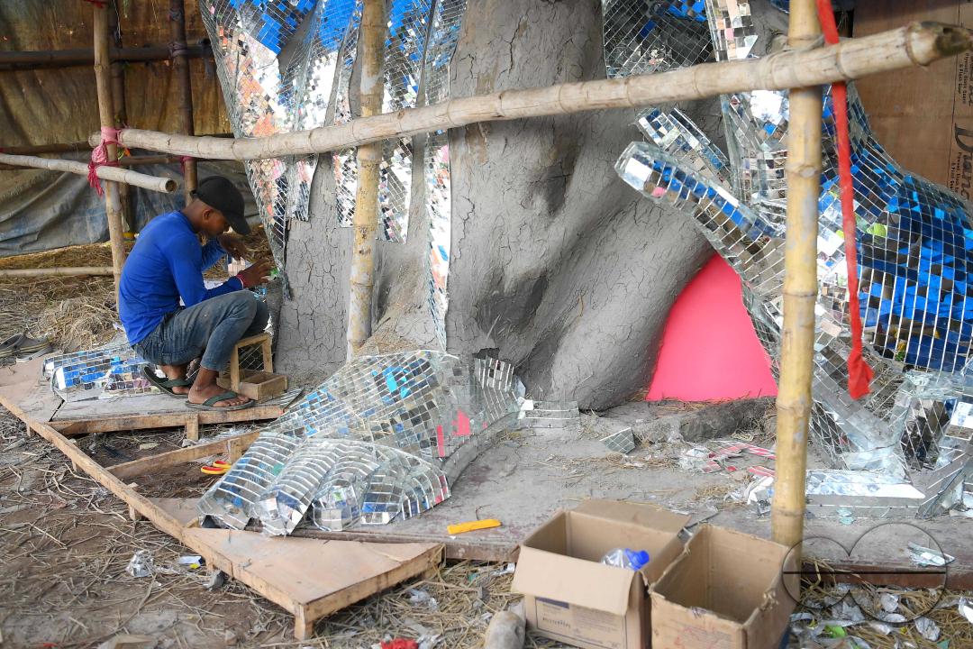An artist is pasting glass pieces to make a 41 feet tall Ganesh idol, fully covered by glass, ahead of Ganesh Chaturthi festival in a pandal in Ranir bazar