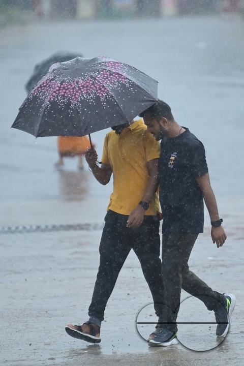 People crossing a deserted road in heavy rain during Cyclone Remal in Agartala