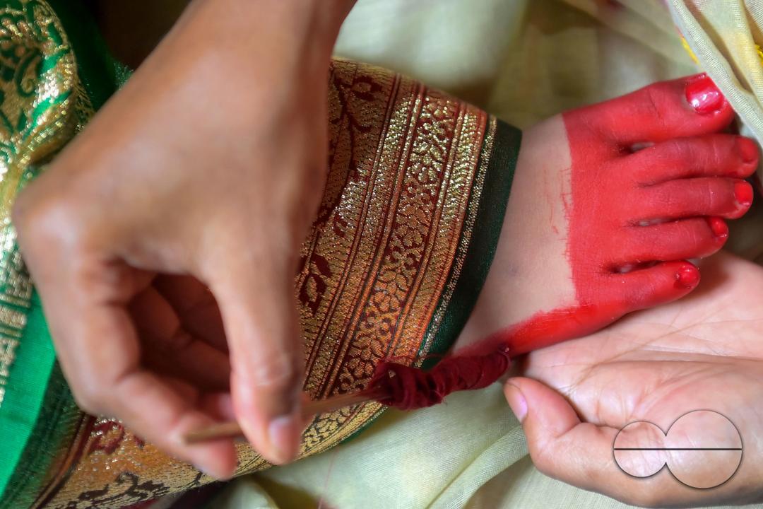 Devotees cover the feet of the nine-year, five-month, and fourteen-day-old Hindu girl, Debalina Chakraborty, with "Alta," a red dye applied to the hands and feet of women during worship and festivals