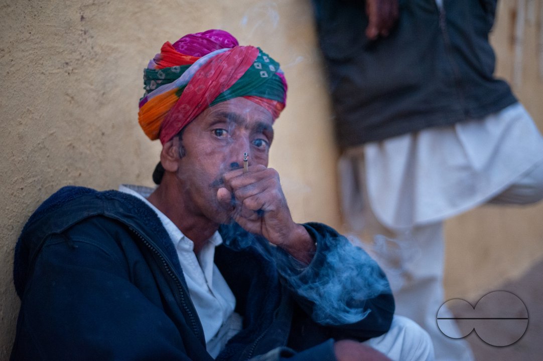 A musician who performs for tourists in the desert smokes a beedi as he waits.