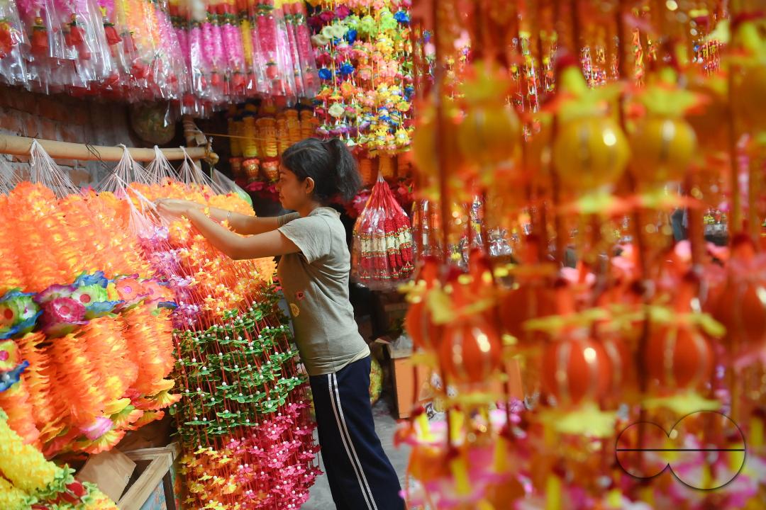 A worker arranging plastic garlands for sale at a stall ahead of the festive