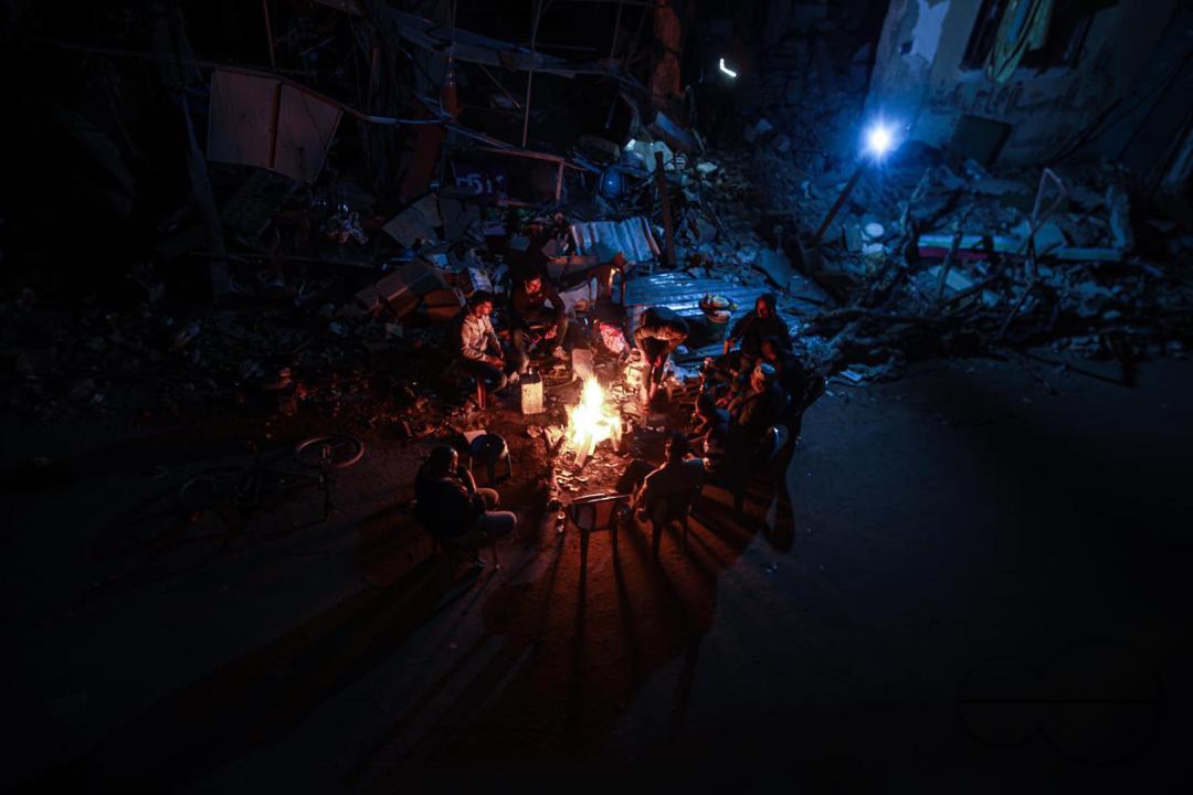 Palestinian citizens sit in front of their destroyed homes and light fires on the third day of the humanitarian truce, east of the city of Khan Yunis