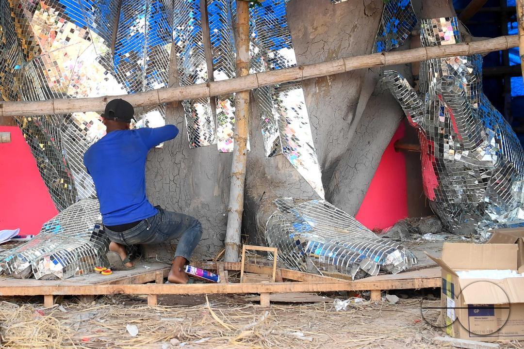 An artist is pasting glass pieces to make a 41 feet tall Ganesh idol, fully covered by glass, ahead of Ganesh Chaturthi festival in a pandal in Ranir bazar