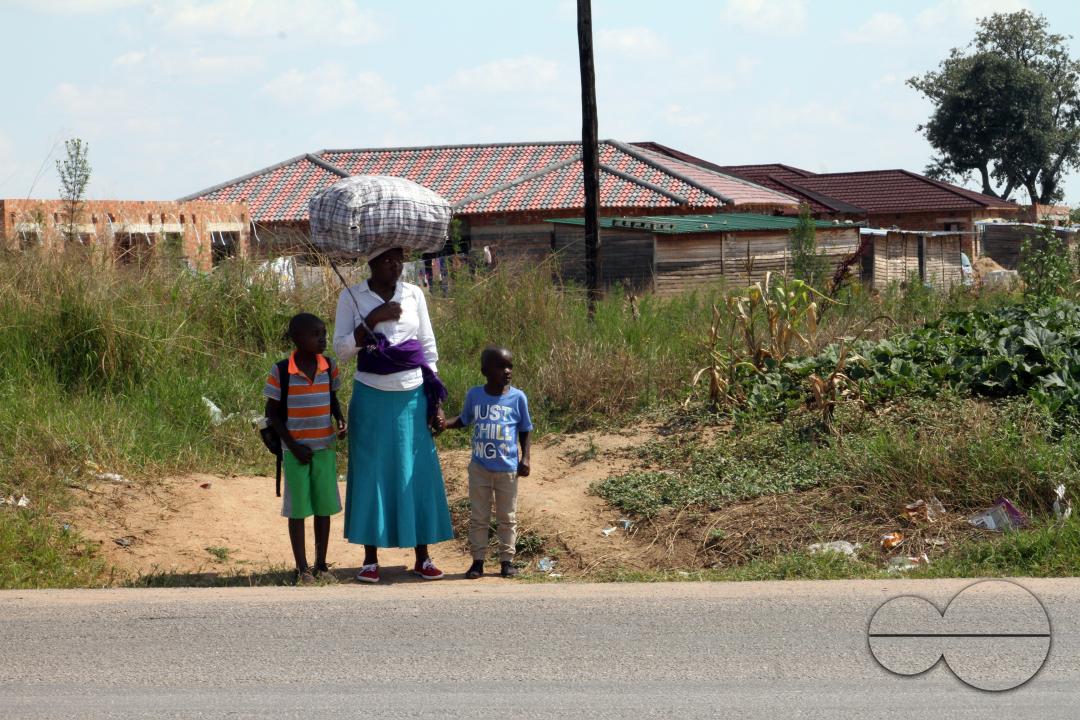 A woman is waiting to cross the busy Beatrice Road near Hopeley Settlement in Harare