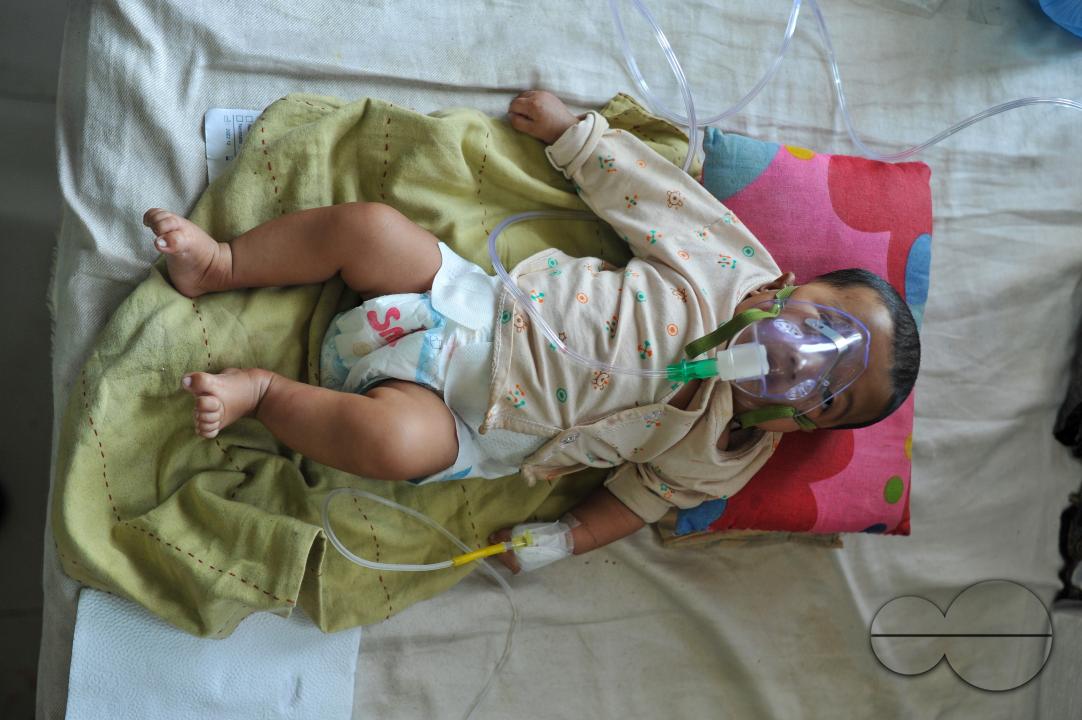 A senior nurse is providing medical care to a child in Sylhet MAG Osmani Medical College Hospital