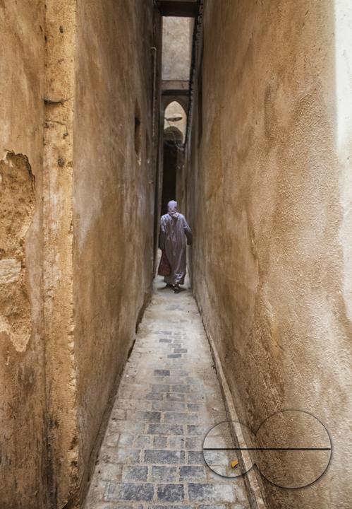 A man walking along the narrow medina streets of Fez