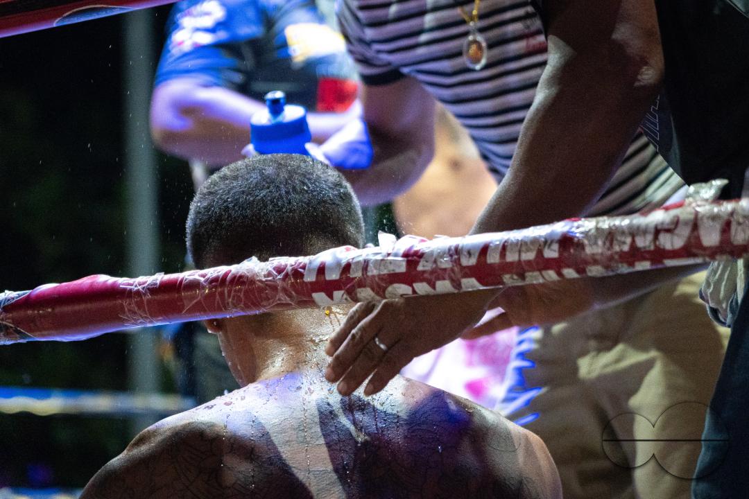 The trainer places his hand behind the back of his sweaty boxer Petch Si Nel (L) who was knocked out by Frame Payak (not in the picture), during the Muay Thai Fights, onKoh Chang Island, Thailand.