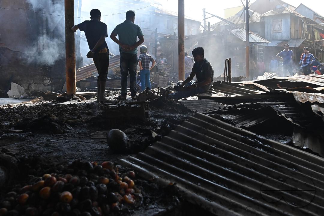 Shop owners and vendors are seen in front of their burnt shops and vegetables stalls in Battala market, the second biggest market in Tripura