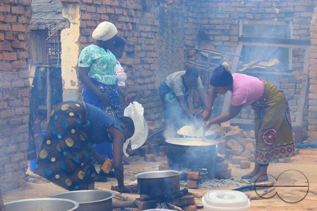 Women are seen manning pots on open fires as they prepare food for a party in Mchinji District