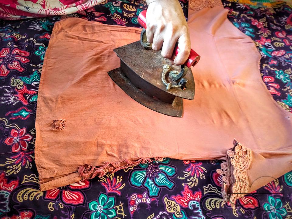 A woman ironing with an old fashioned charcoal iron at the Balukhali refugee camp