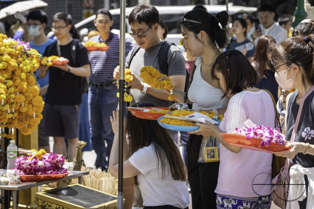 In the heart of downtown Bangkok, Thai locals and tourists alike gather at the Erawan Shrine, each with their basket of offerings, uniting in prayer and reverence
