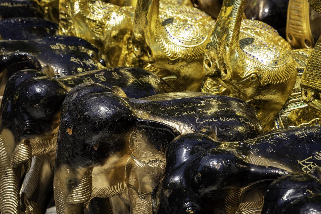 A detailed close-up of a ceramic elephant, displayed at the Erawan Shrine in downtown Bangkok, bearing a price tag of 20,000 THB (approximately 550 dollars)