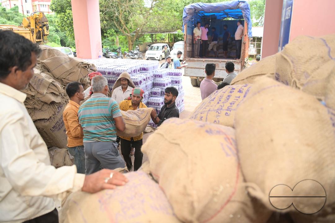 Laborers are carrying packets of food and stacking them in a truck as government officials and workers prepare food packets to be distributed by NDRF (National Disaster Response Force) personnel from helicopters to flood victims in different parts of Tri