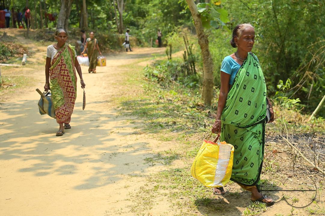 People transporting household items in makeshift tents at Panisagar's reserve forest area