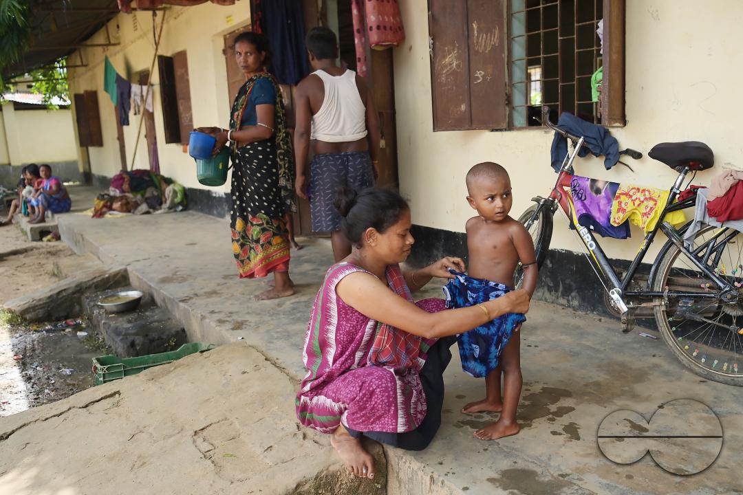 A mother and son are trying to dry clothes at a temporary relief camp at Pratapgarh English Medium School in Agartala